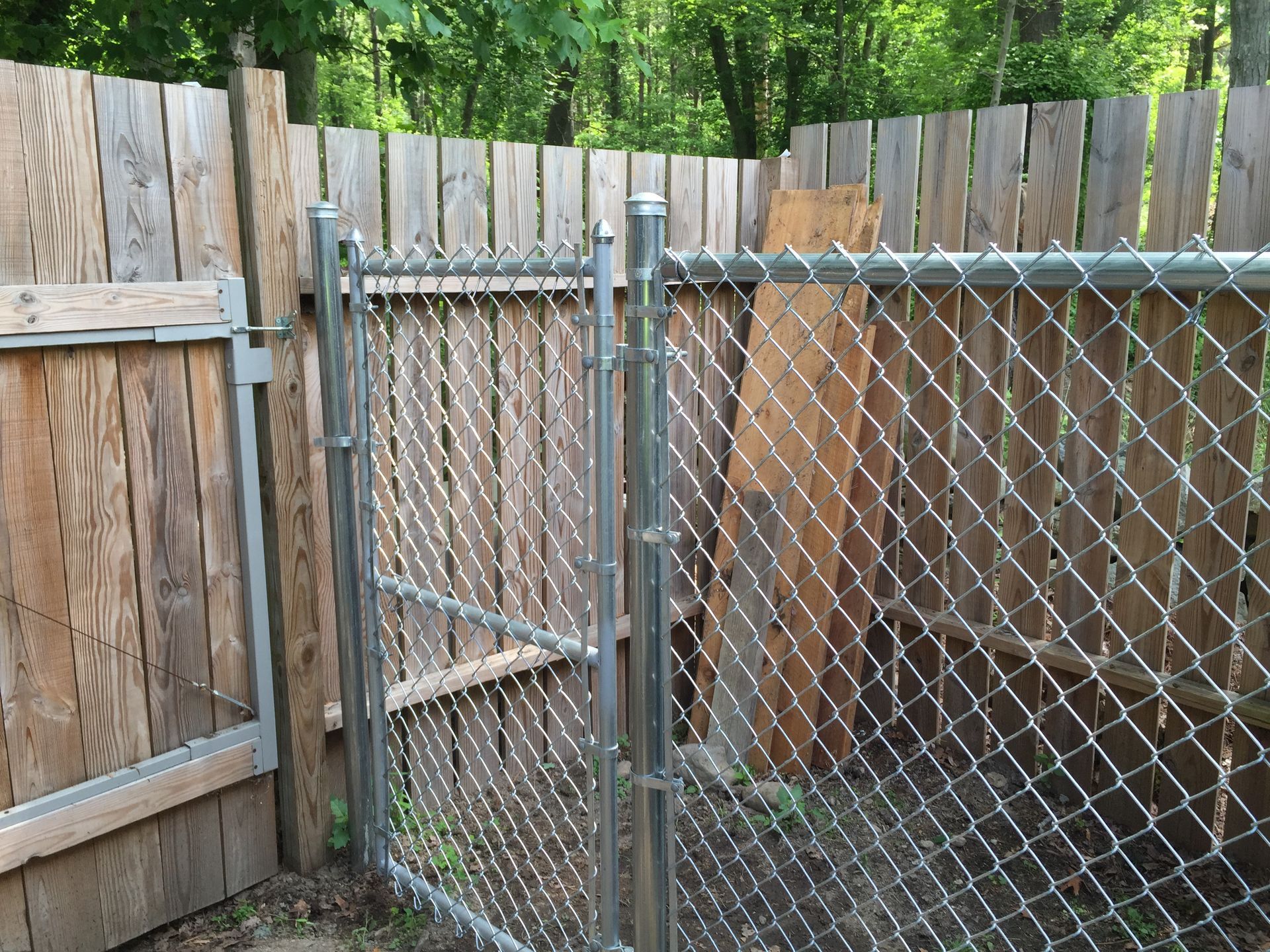 A chain link fence with a wooden fence behind it