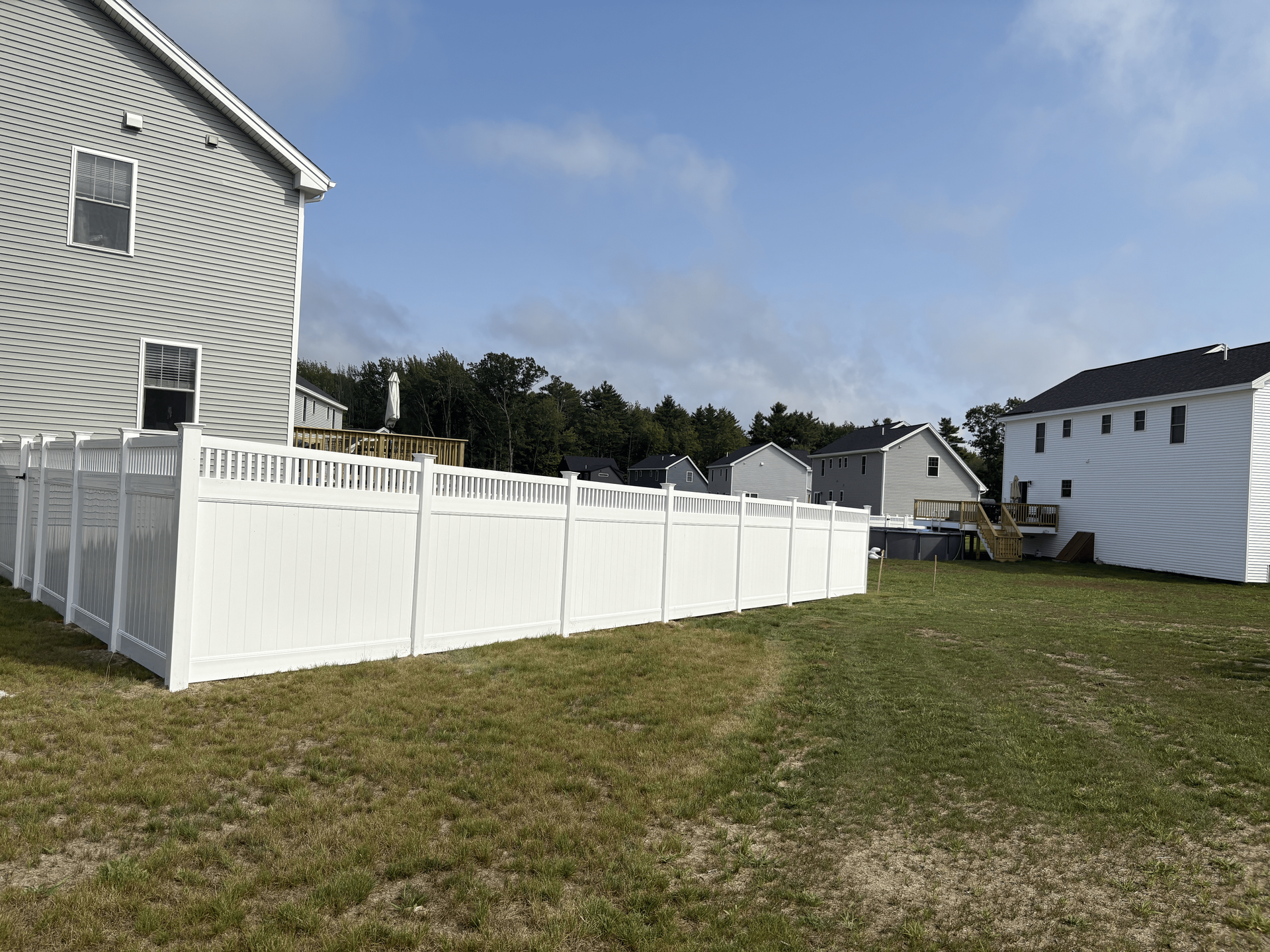 There is a white fence in the backyard of a house.