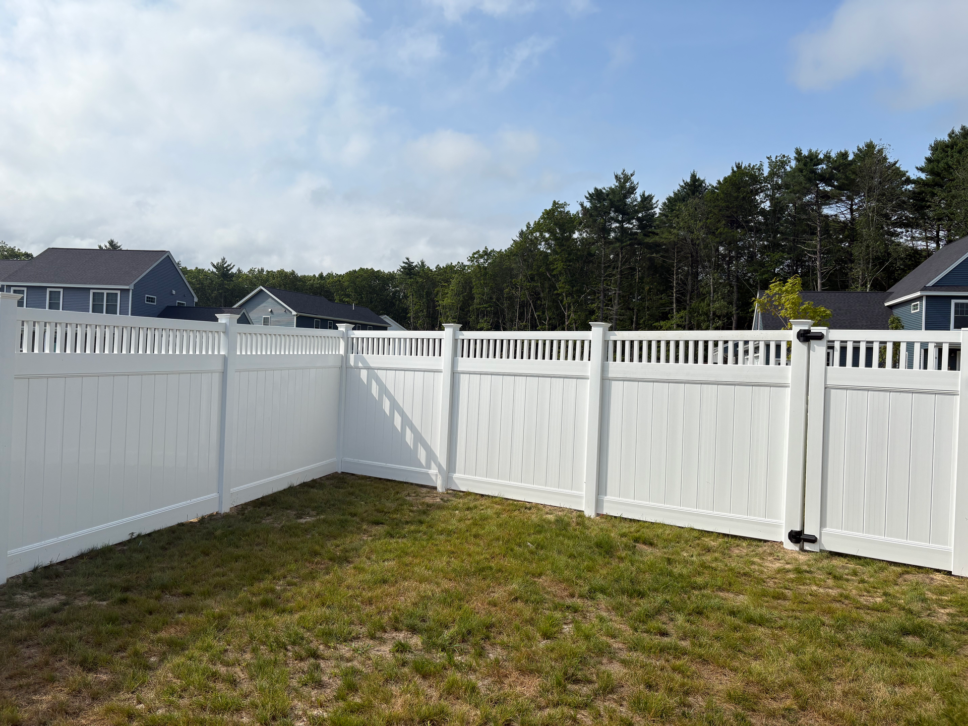 A white fence surrounds a lush green yard.