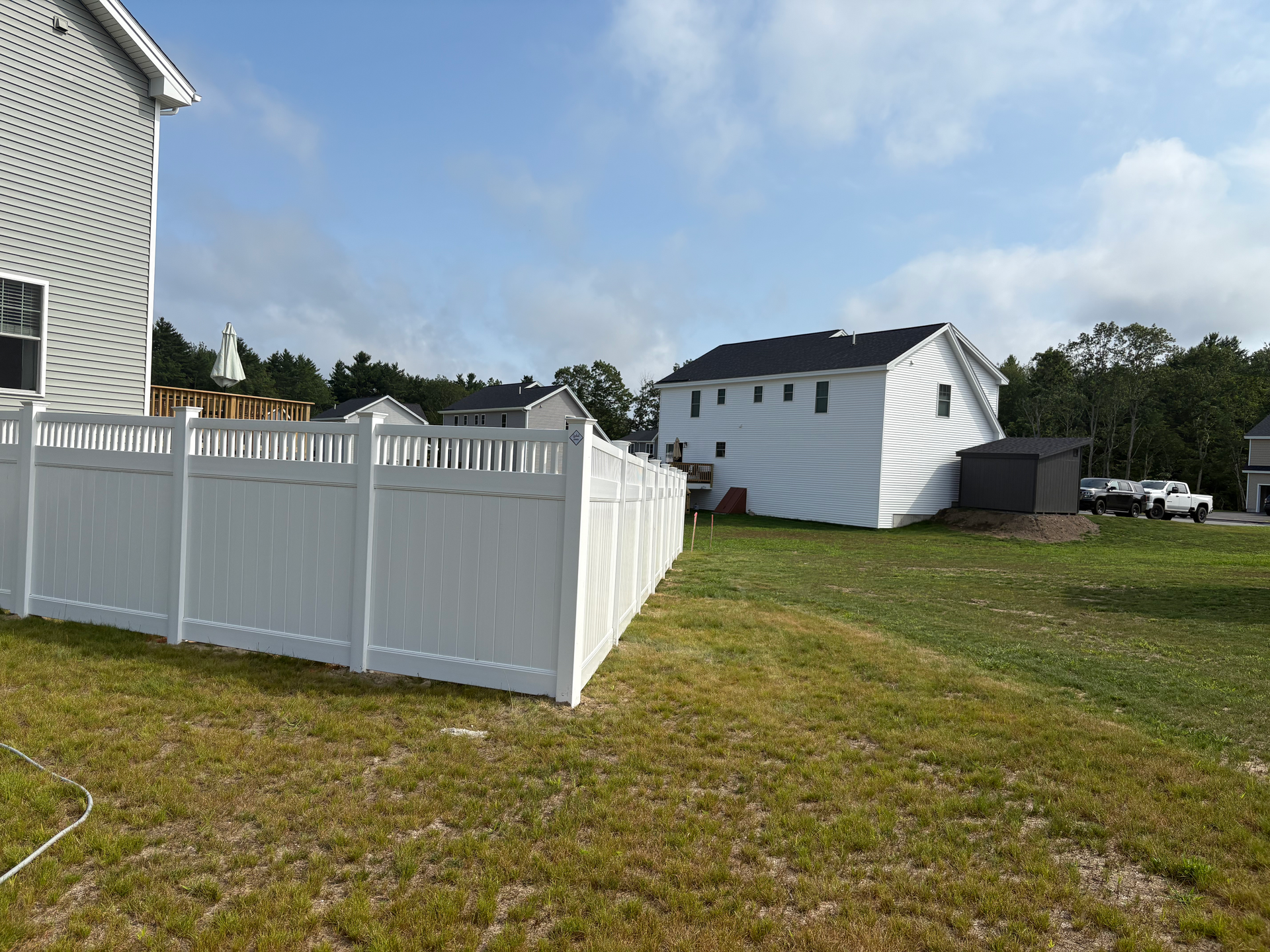 There is a white fence in the backyard of a house.