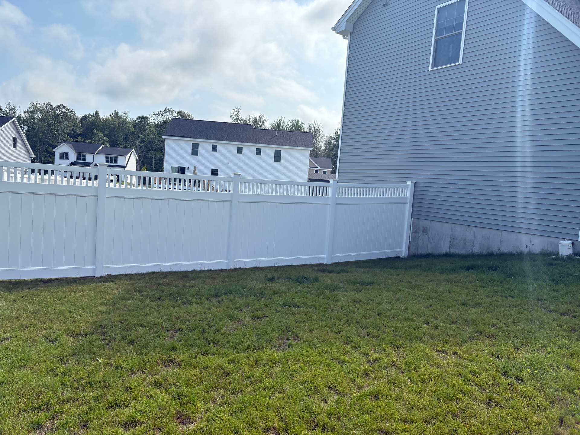 There is a white fence in the backyard of a house.