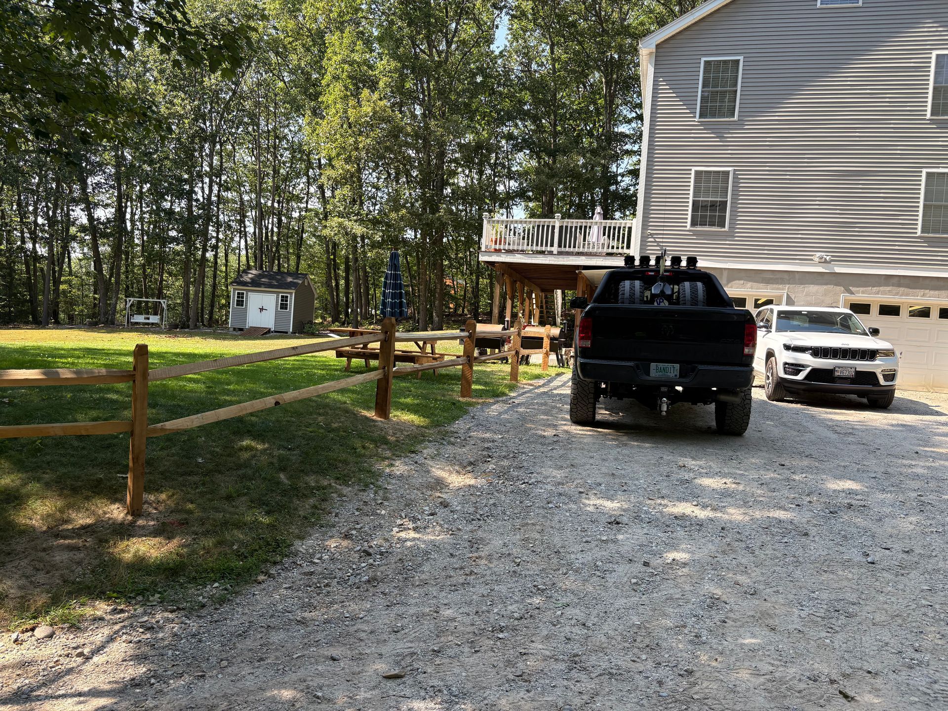 A truck is parked in a gravel driveway in front of a house.