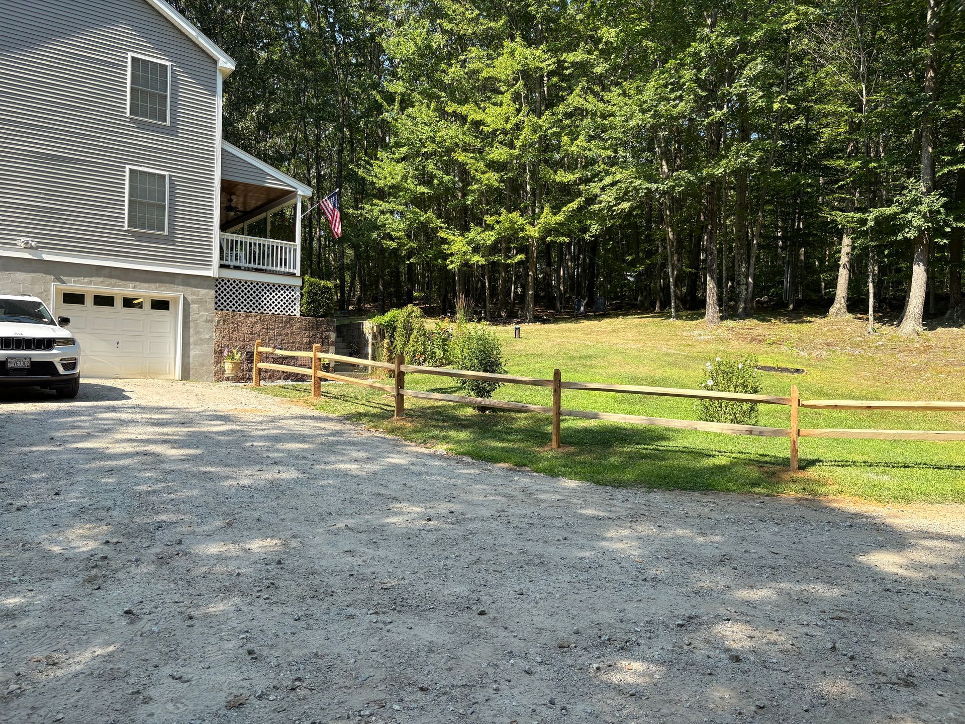 A car is parked in a gravel driveway in front of a house.