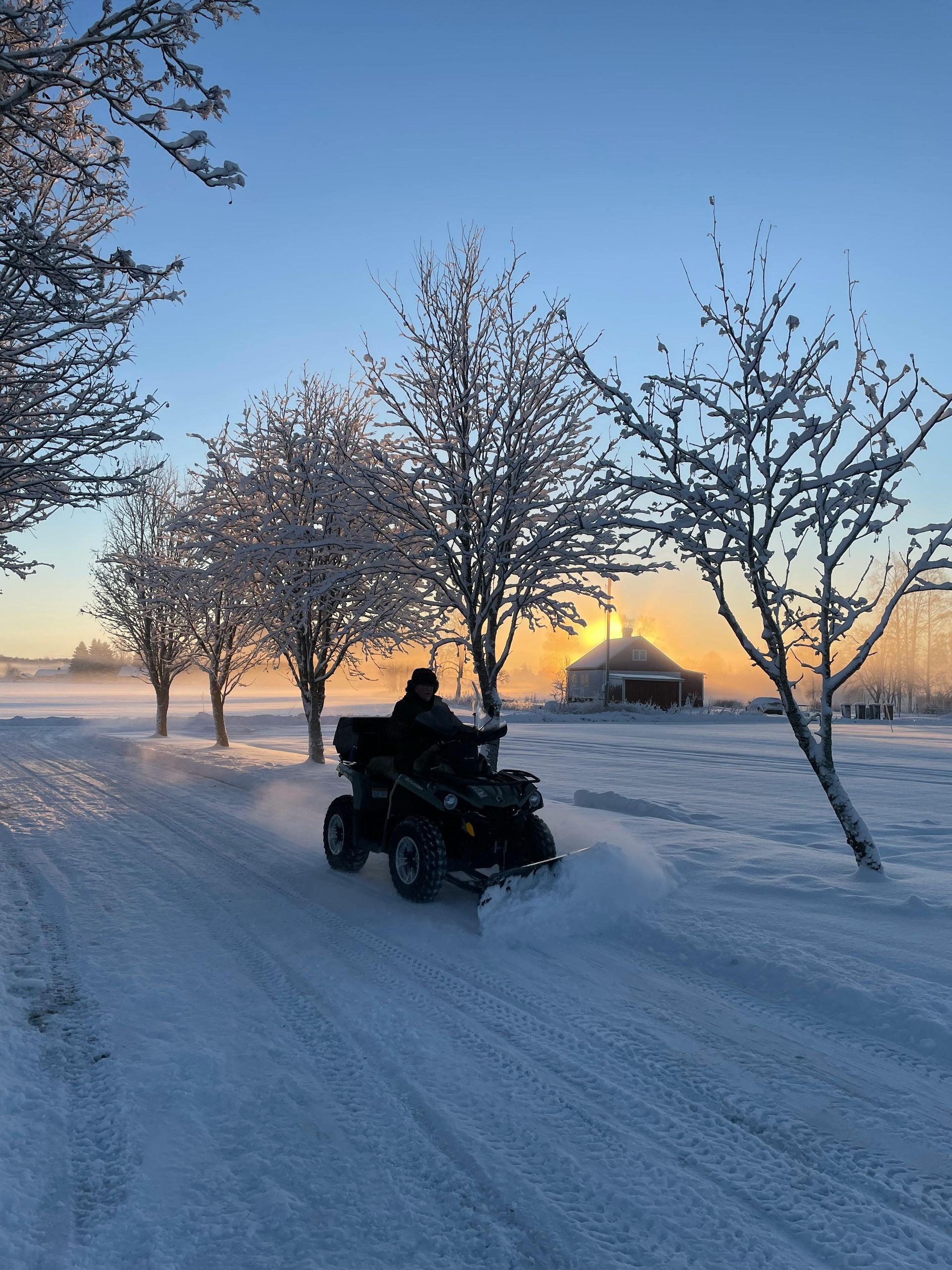 A man is riding an atv on a snowy road