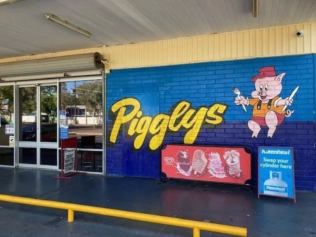 Pigglys Grocery Store Entrance With a Pig Mascot Holding Utensils — Pigglys Supermarket, Takeaway & Bottle Shop in The Gap, NT