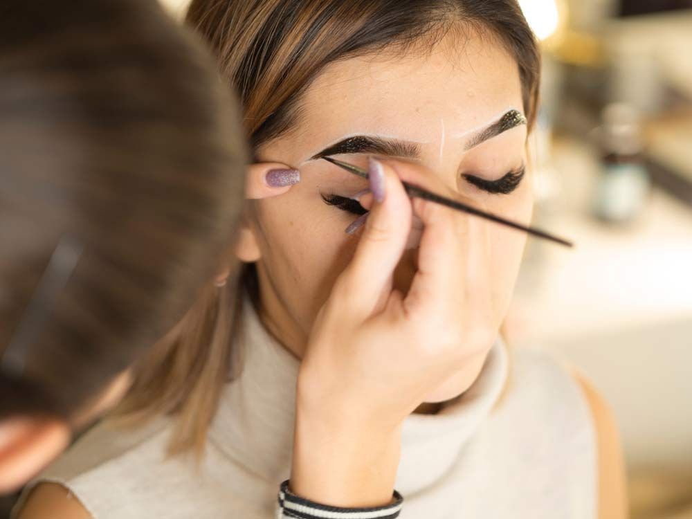 A Woman Is Getting Her Eyebrows Painted By A Makeup Artist — Envy Cosmetic Collective in Maitland, NSW