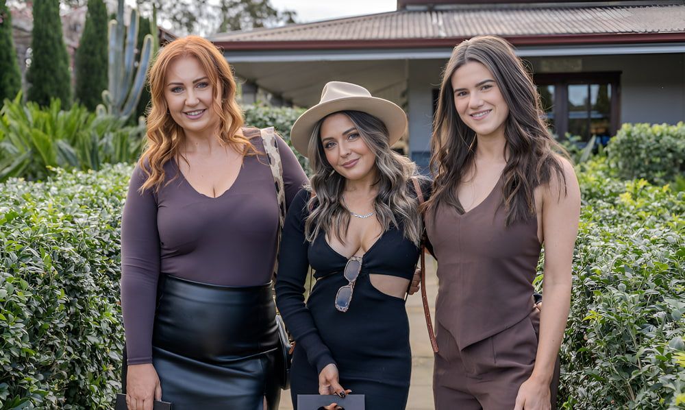 Three Women Are Posing For A Picture In Front Of A House — Envy Cosmetic Collective in Maitland, NSW
