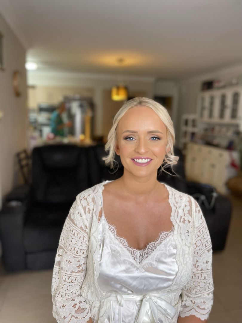 A Woman In A White Lace Dress Is Smiling In A Living Room — Envy Cosmetic Collective in Maitland, NSW