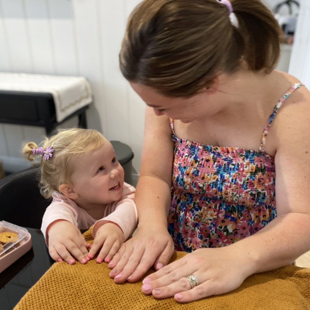 A Woman And A Little Girl Are Sitting At A Table Looking At Each Other — Envy Cosmetic Collective in Maitland, NSW