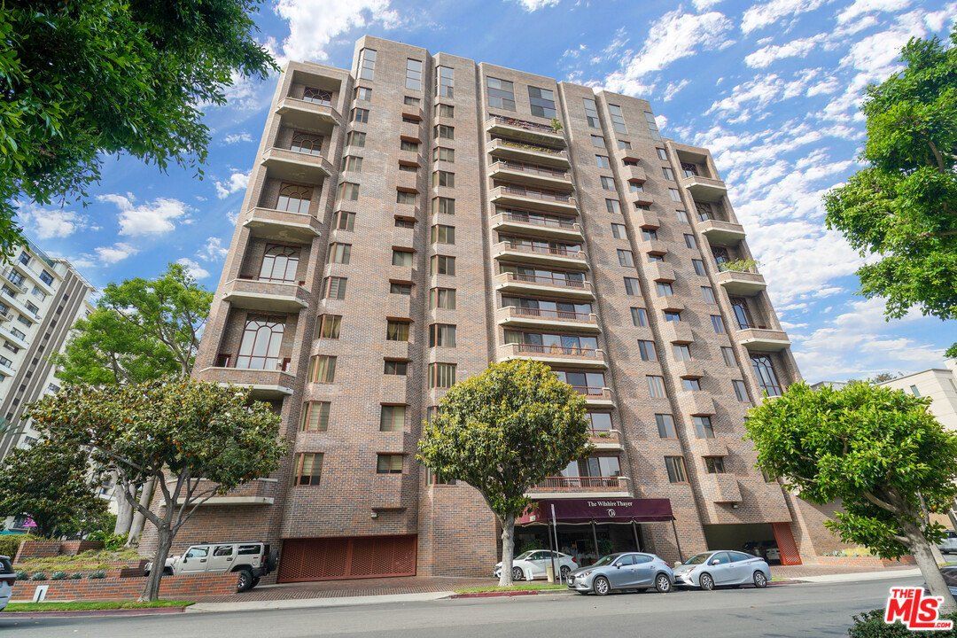 A tall building with cars parked in front of it.
