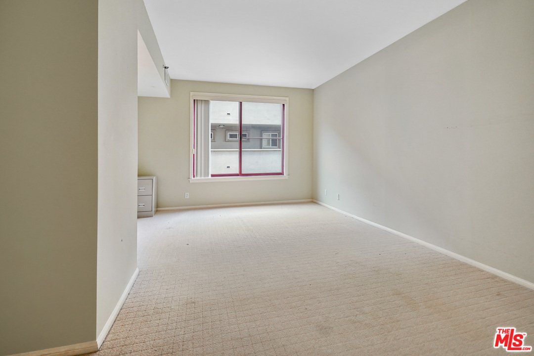 An empty living room with white walls and a window.