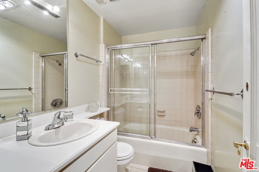 A bathroom with a sink , toilet , shower and mirror.
