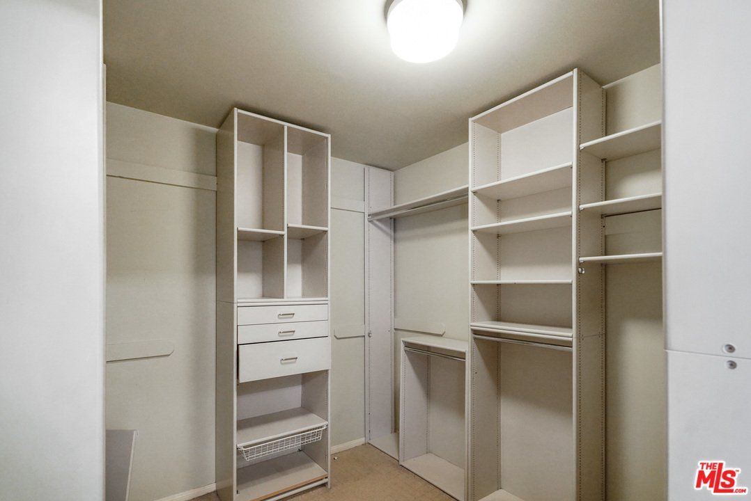 A walk in closet with lots of shelves and drawers.