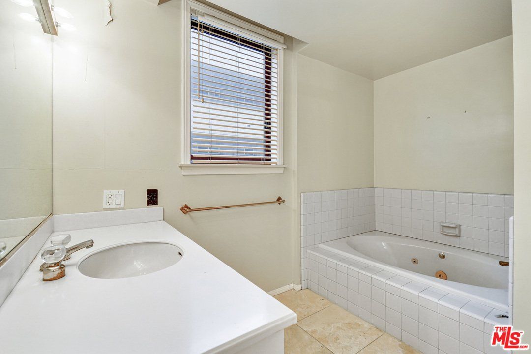 A bathroom with a sink , tub , mirror and window.