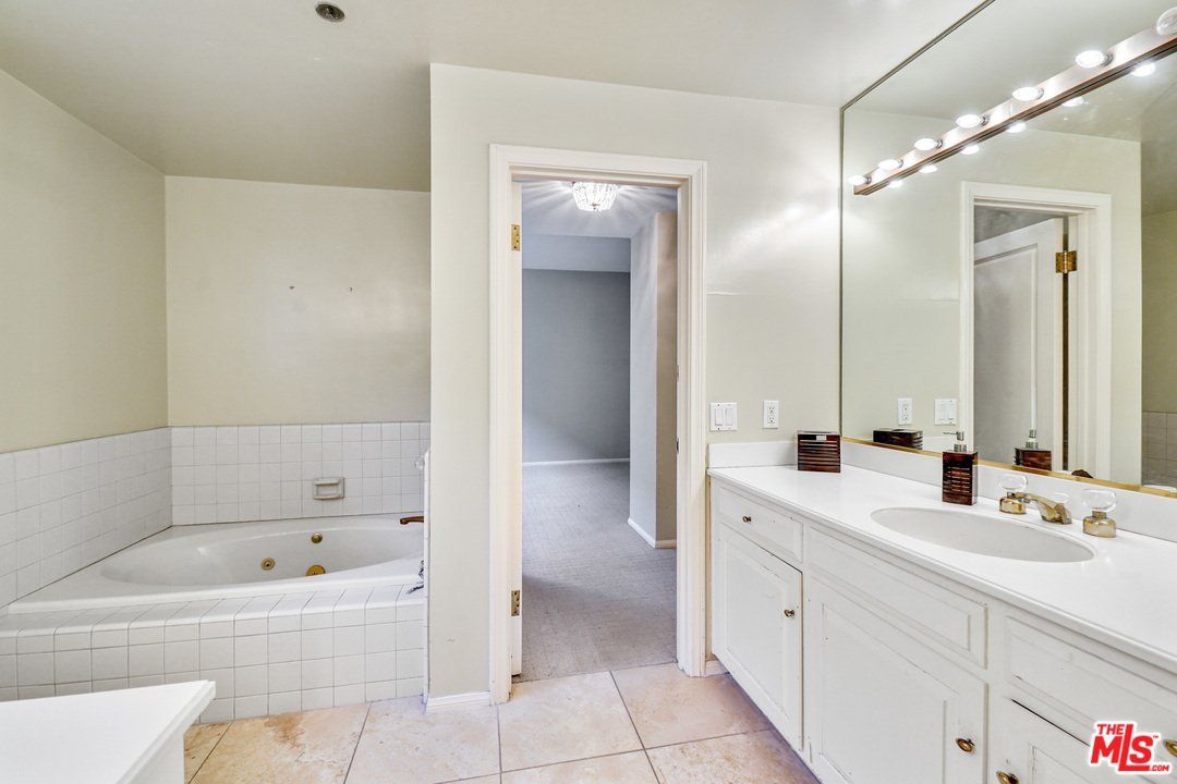 A bathroom with a jacuzzi tub , sink and mirror.