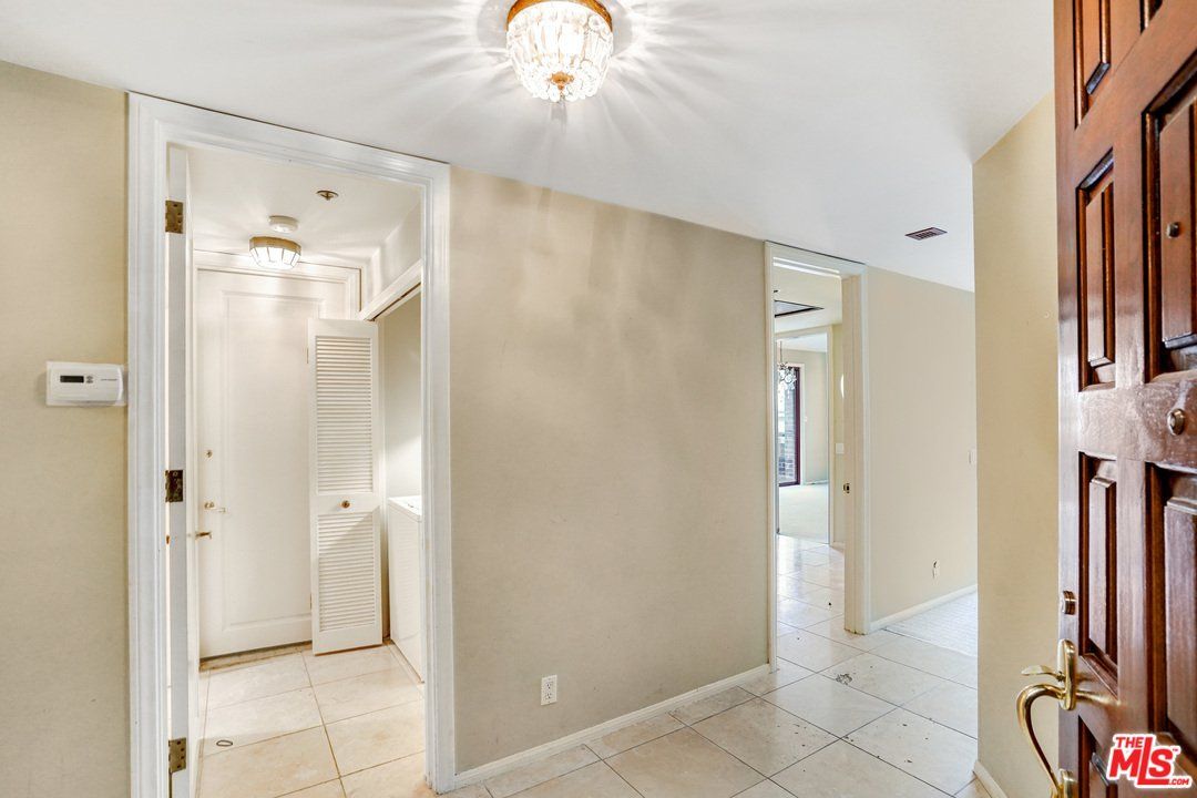 A hallway in a house with a wooden door leading to a bathroom.