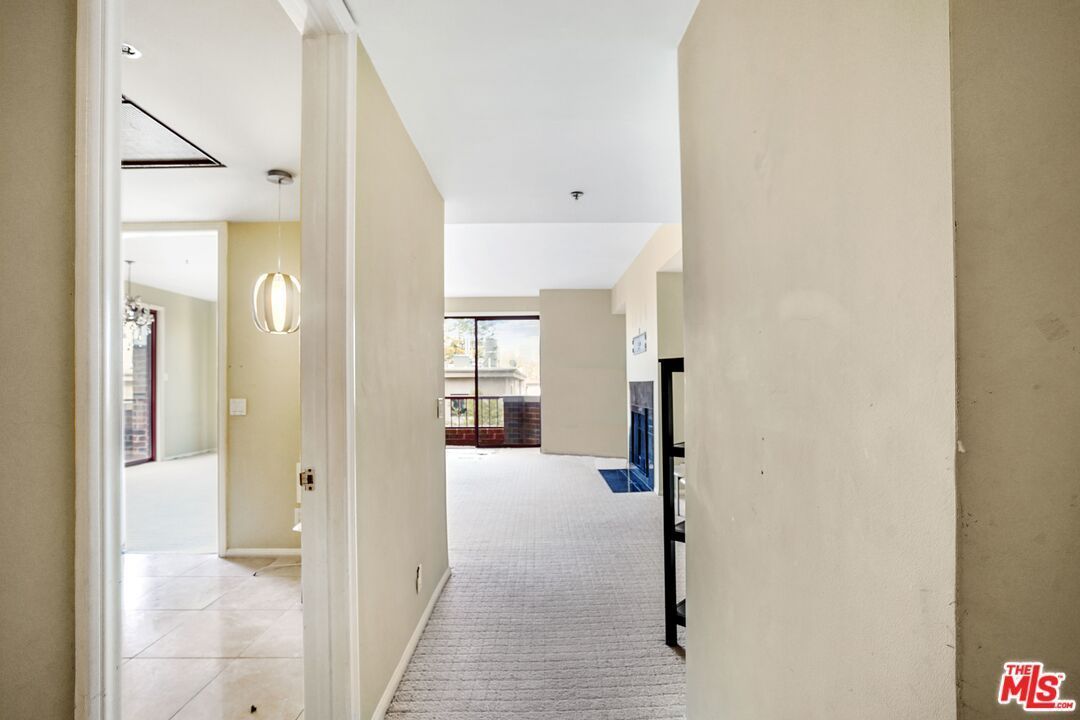 A hallway in a house with a sliding glass door leading to a living room.