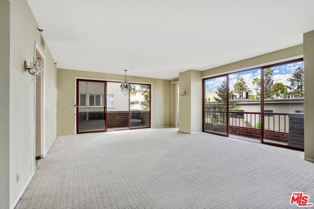 An empty living room with sliding glass doors and a balcony.