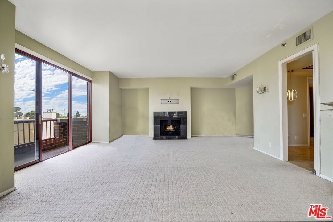 An empty living room with a fireplace and sliding glass doors.