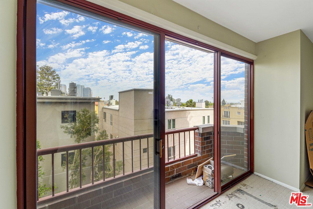 A balcony with sliding glass doors and a view of a city.