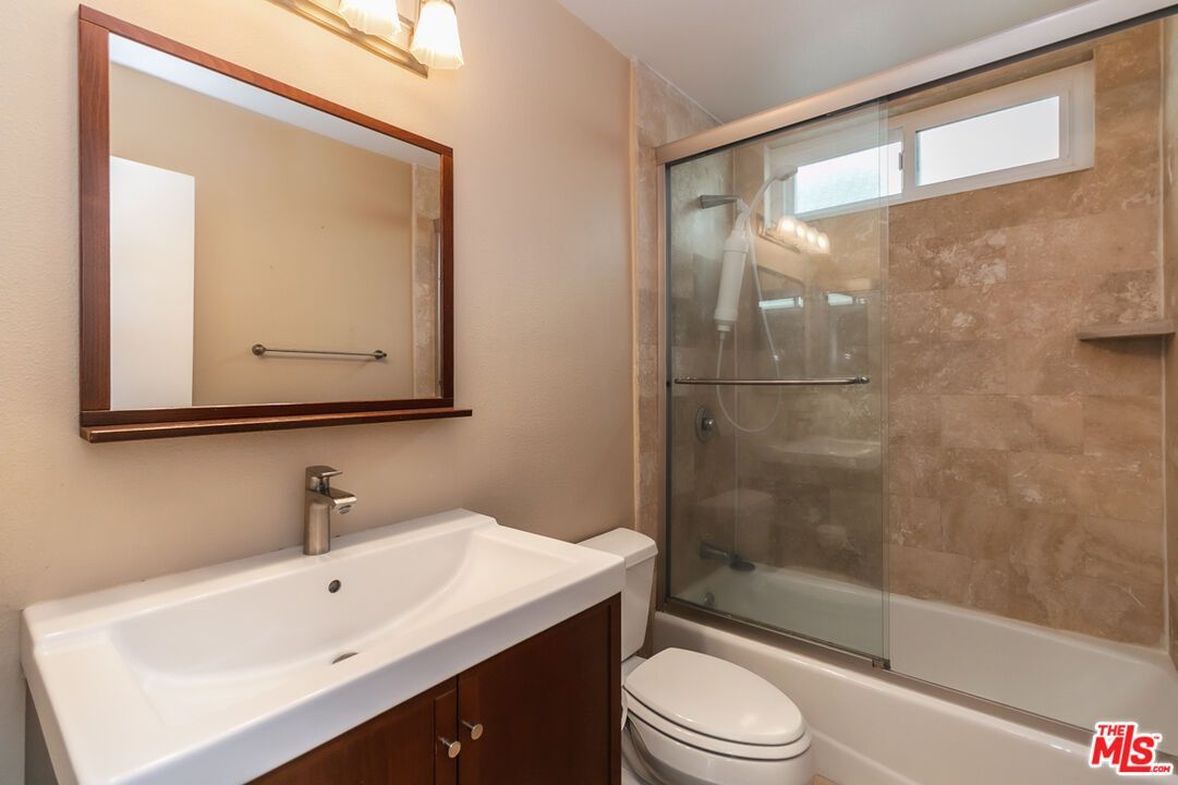 A bathroom with a sink , toilet , shower and mirror.