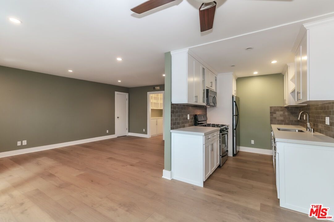 An empty room with a kitchen and a ceiling fan