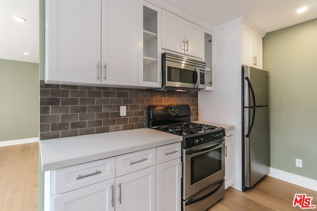 A kitchen with stainless steel appliances and white cabinets