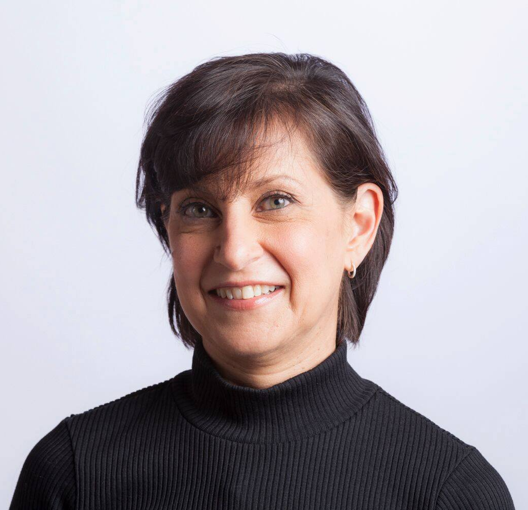 A woman in a black sweater is smiling for the camera