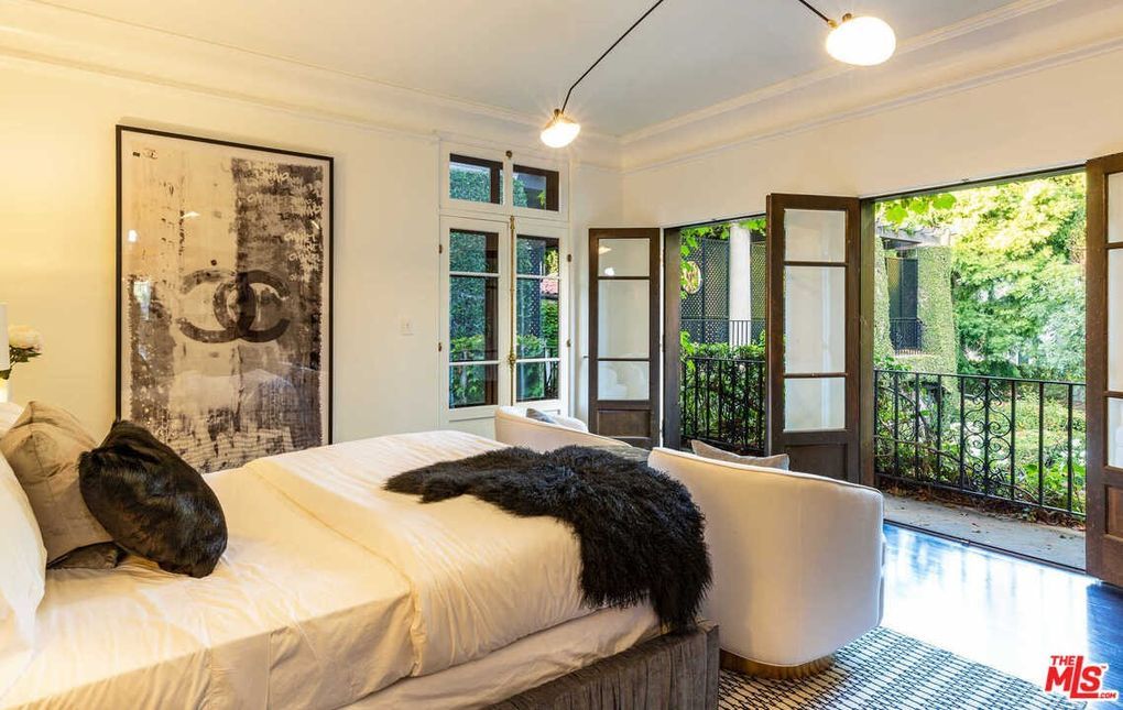 A bedroom with a large bed , a couch , and a balcony.