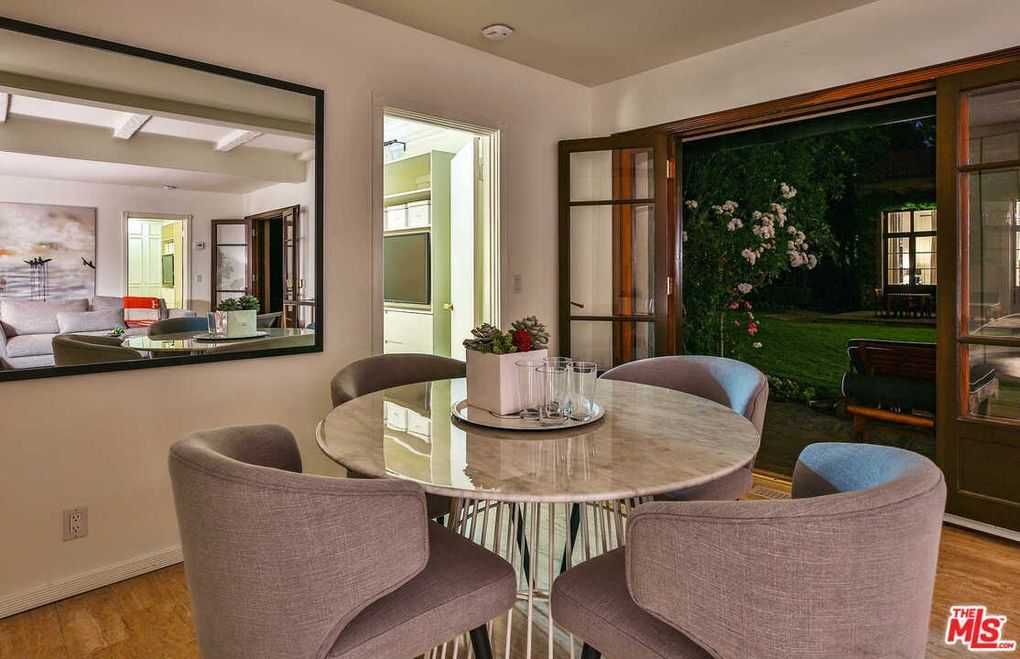 A dining room with a round table and chairs and a large mirror.