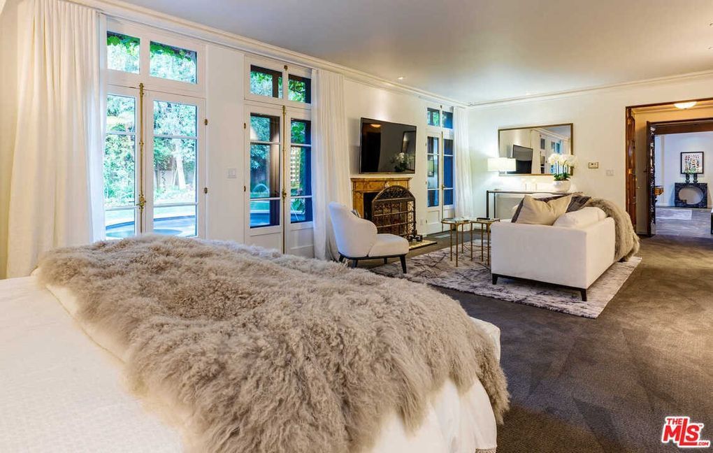 A bedroom with a bed , couch , television and fireplace.