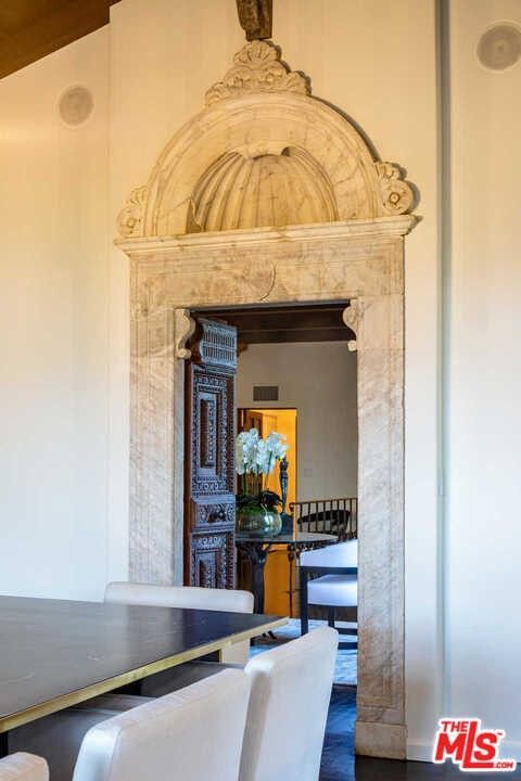 A dining room with a table and chairs and a marble archway