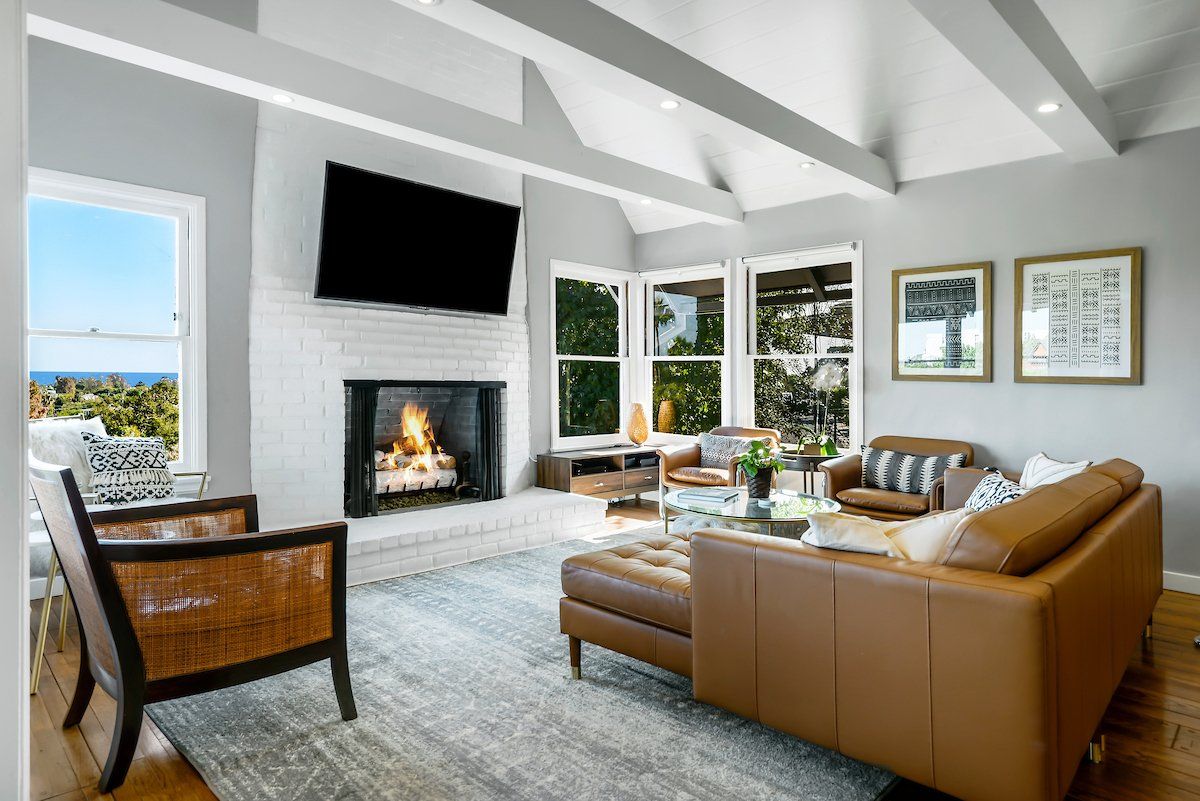 A living room with a couch , chairs , a fireplace and a flat screen tv.