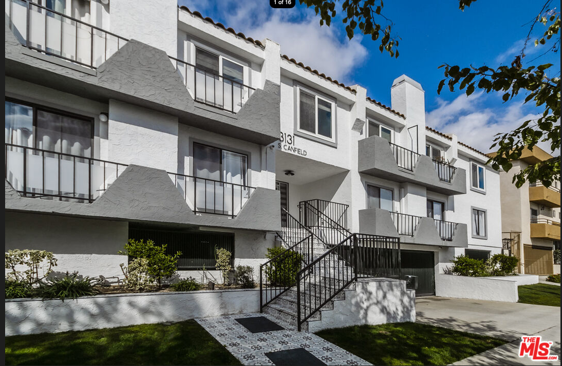 A white apartment building with stairs leading up to it