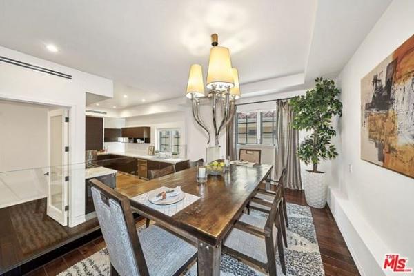 A dining room with a wooden table and chairs and a chandelier.