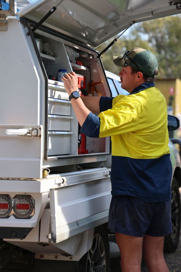 Man in a yellow/navy shirt reaching into a truck bed with shelves, outdoors -Chill-Rite Refrigeration and Air Conditioning in Dubbo, NSW