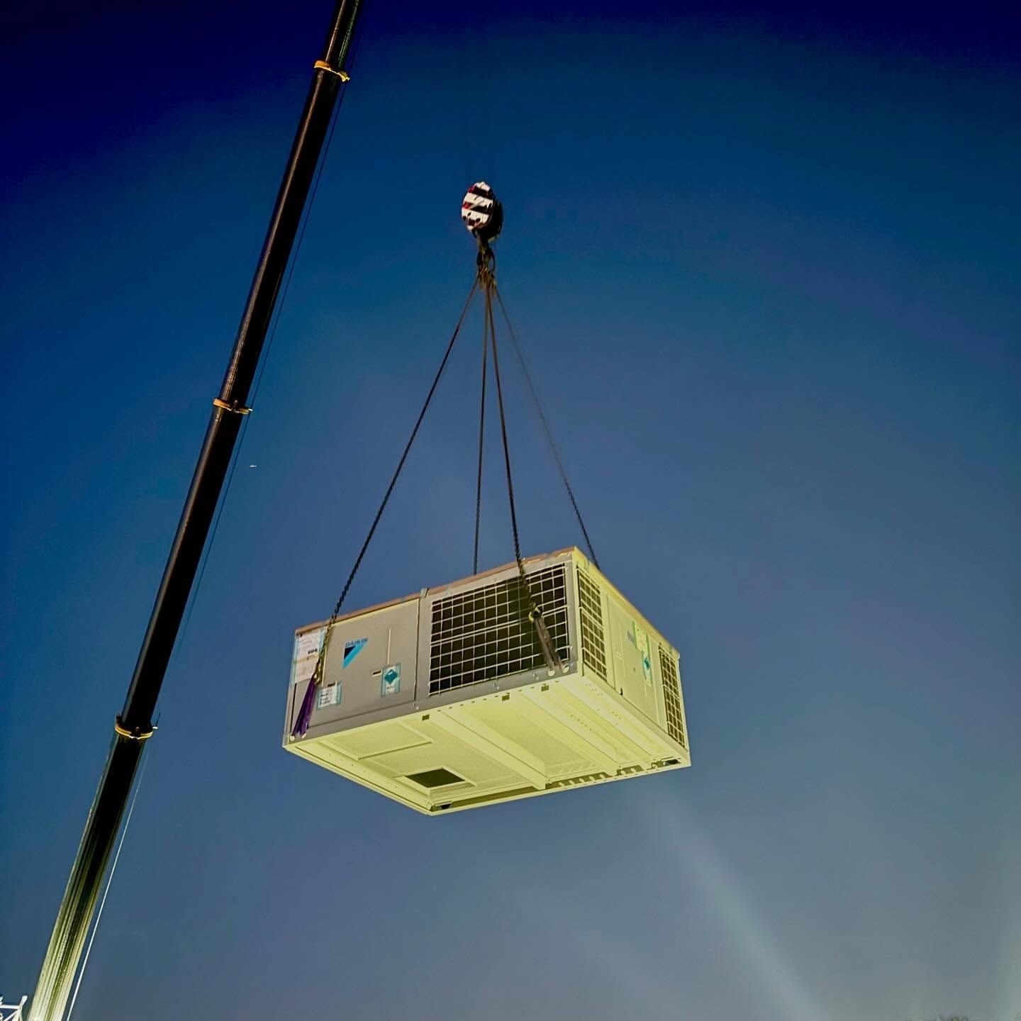 A Large Box is Being Lifted by a Crane Against a Blue Sky — Chill-Rite Refrigeration and Air Conditioning in Dubbo, NSW