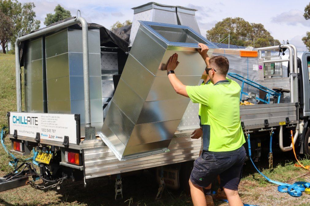 A Man is Lifting a Piece of Metal From the Back of a Truck — Chill-Rite Refrigeration and Air Conditioning in Parkes, NSW