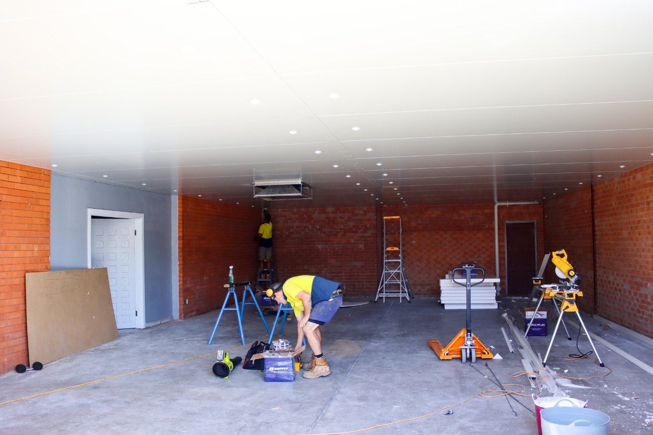 A Man is Working on a Ceiling in a Garage — Chill-Rite Refrigeration and Air Conditioning in Dubbo, NSW