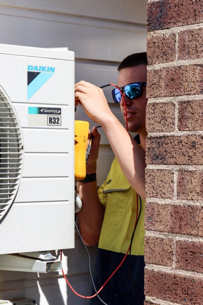 A Man is Working on a Daikin Air Conditioner Outside of a Brick Building — Chill-Rite Refrigeration and Air Conditioning in Tamworth, NSW