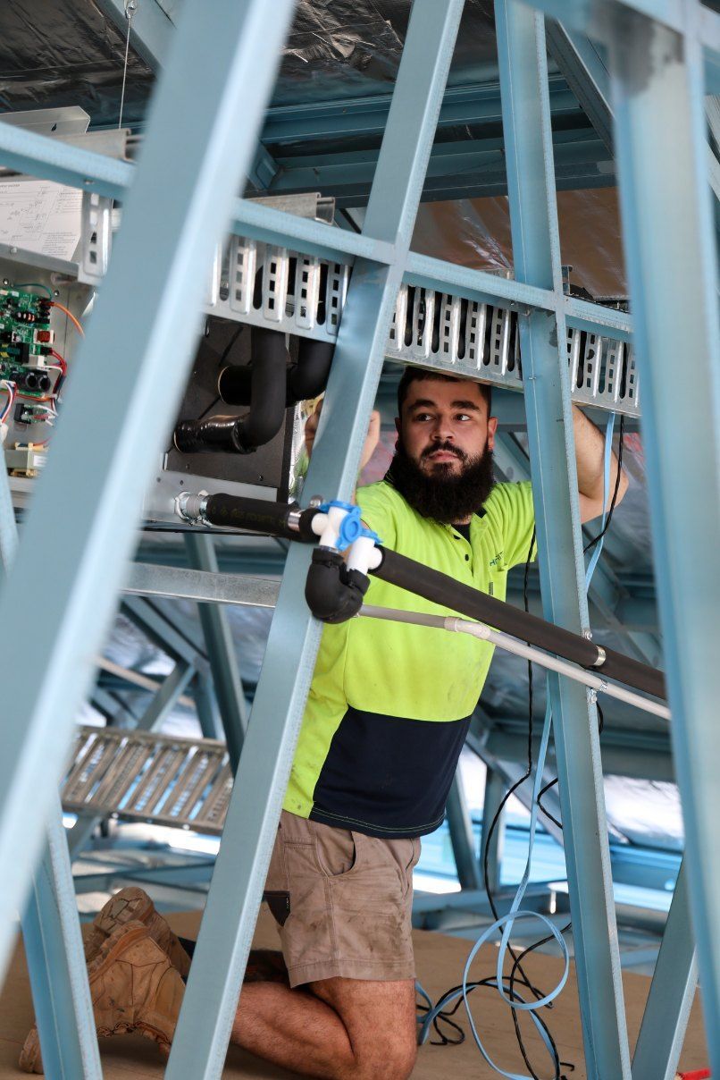 A Man With a Beard is Kneeling Down in a Building Under Construction — Chill-Rite Refrigeration and Air Conditioning in Dubbo, NSW