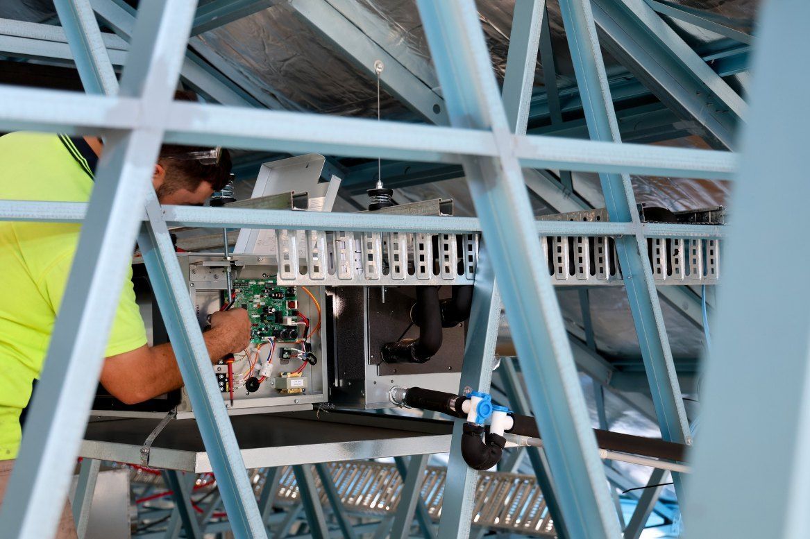 A Man is Working on a Machine in a Building — Chill-Rite Refrigeration and Air Conditioning in Dubbo, NSW