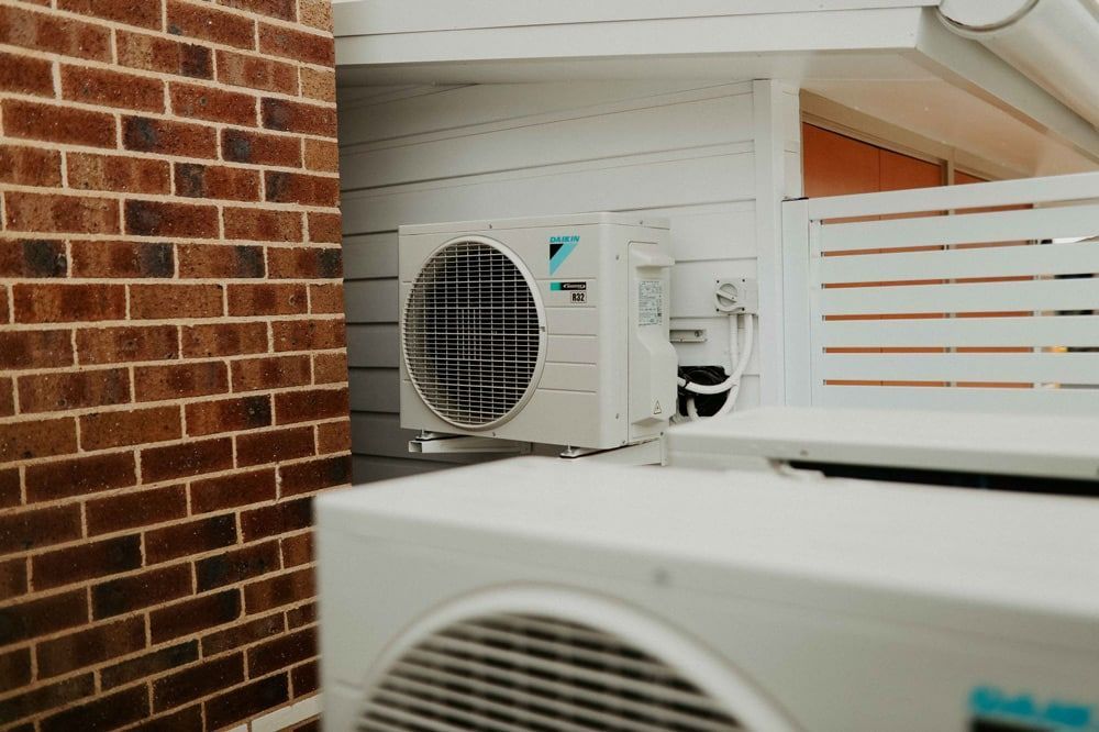 Two Air Conditioners Are Sitting on the Side of a Brick Building — Chill-Rite Refrigeration and Air Conditioning in Dubbo, NSW