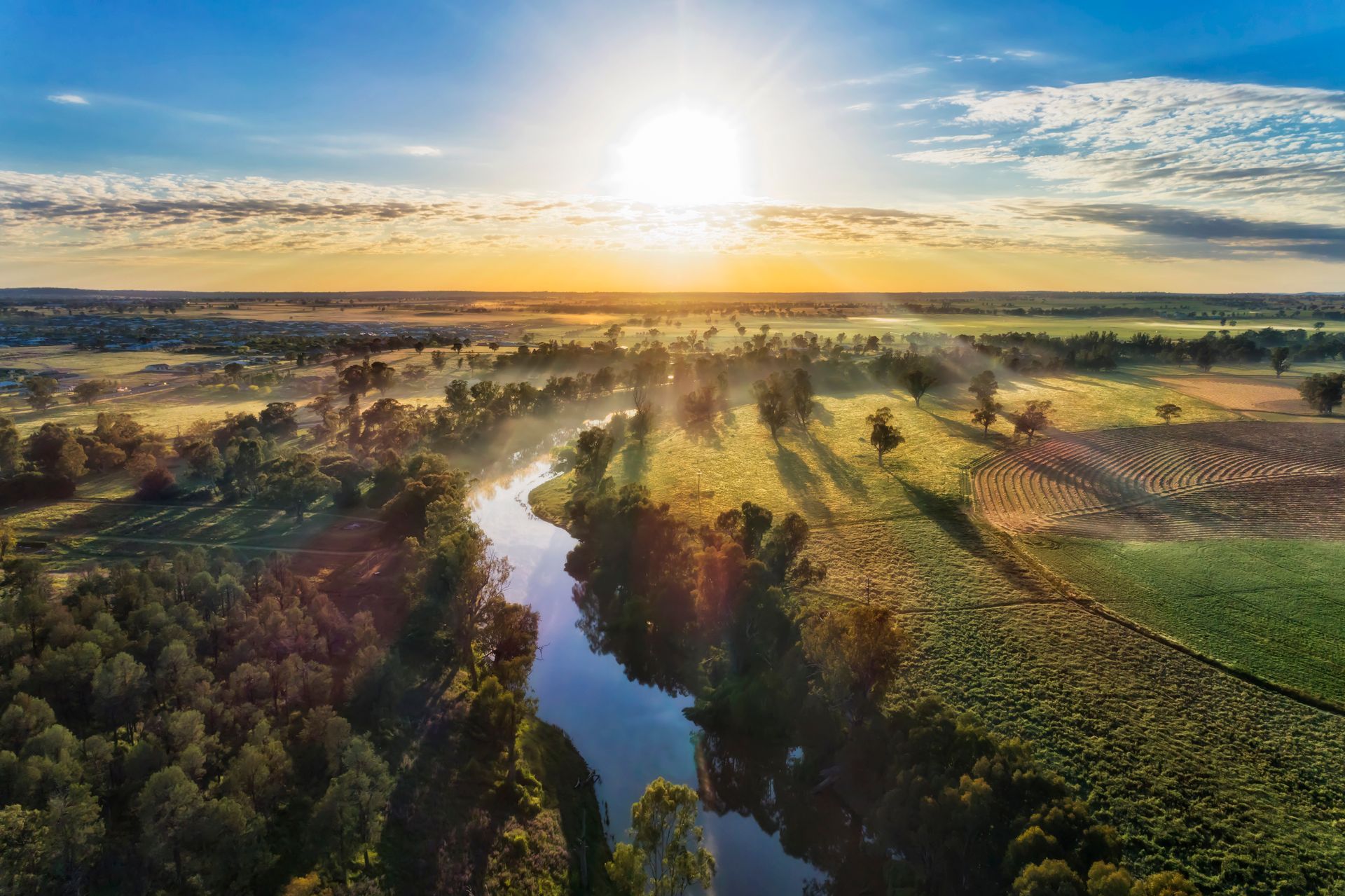 River winds through a lush, green landscape, bathed in the golden light of the setting sun— Chill-Rite Refrigeration and Air Conditioning in Newcastle, NSW
