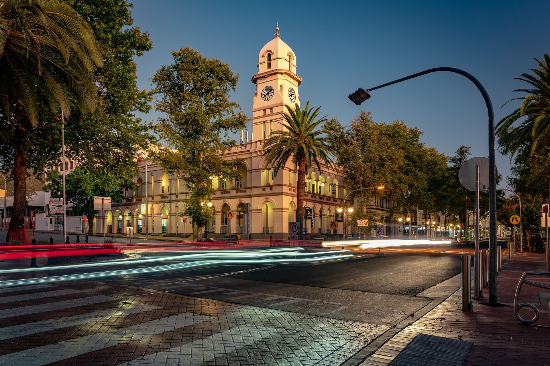 Historic building with clock tower at dusk, traffic lights streak. Palm trees and street lights— Chill-Rite Refrigeration and Air Conditioning in Newcastle, NSW