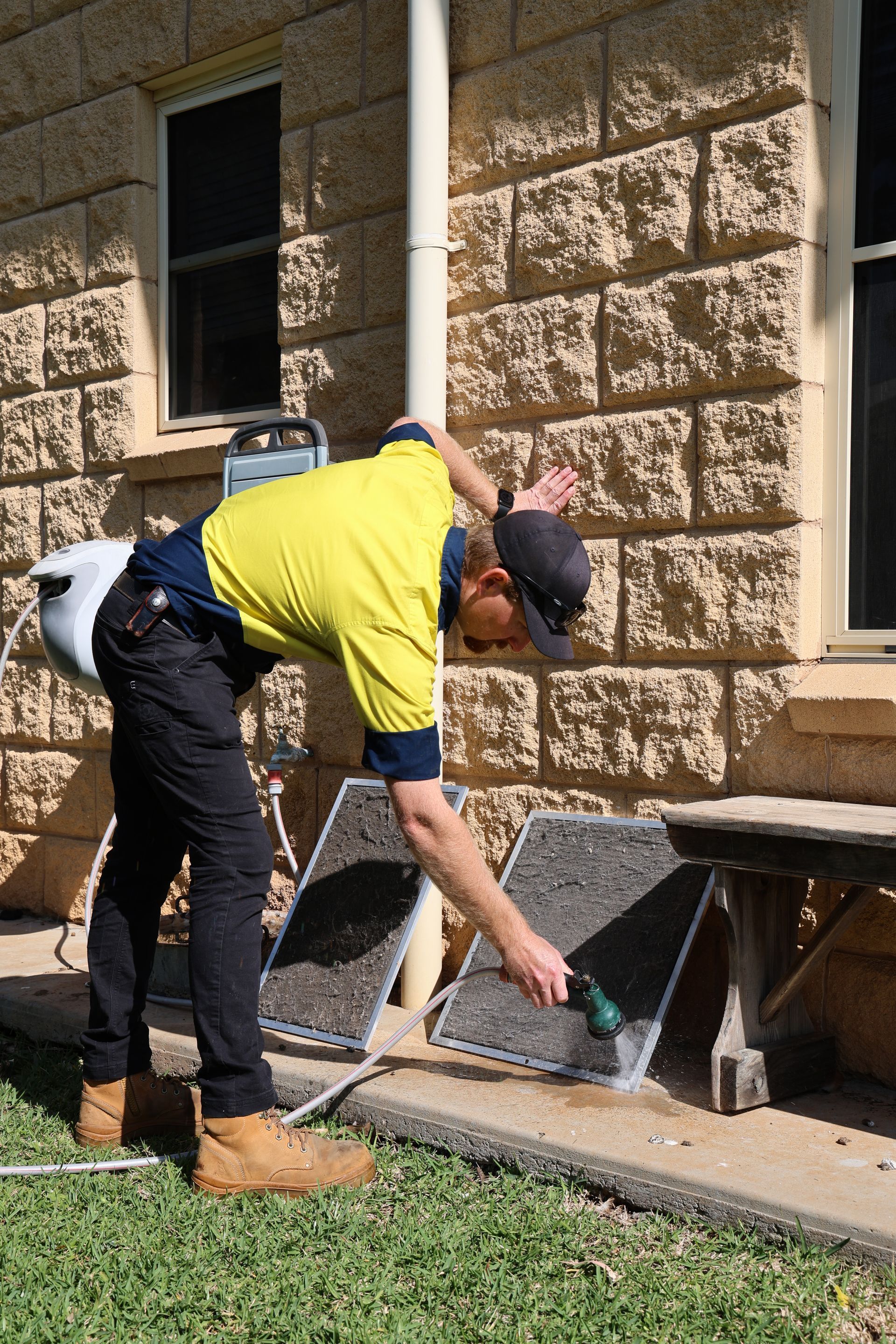 A person washes two vent covers outside a brick building— Chill-Rite Refrigeration and Air Conditioning in Dubbo, NSW