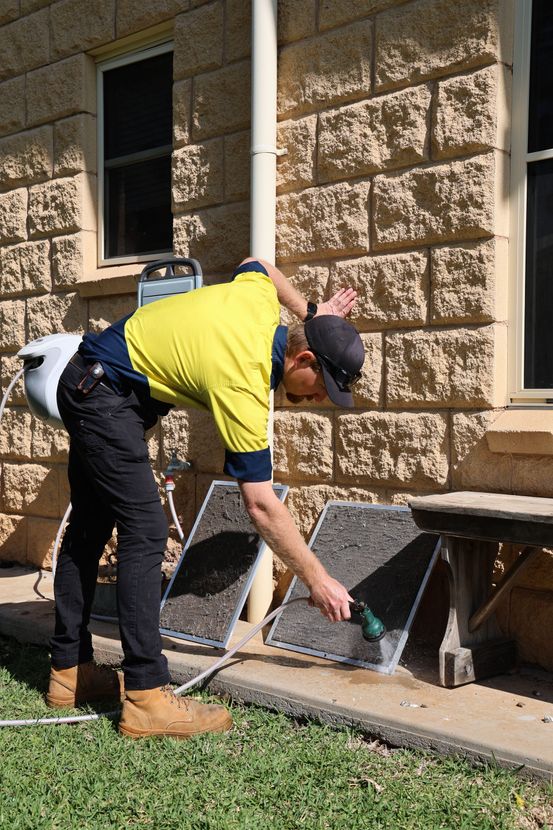A person washes two vent covers outside a brick building— Chill-Rite Refrigeration and Air Conditioning in Dubbo, NSW