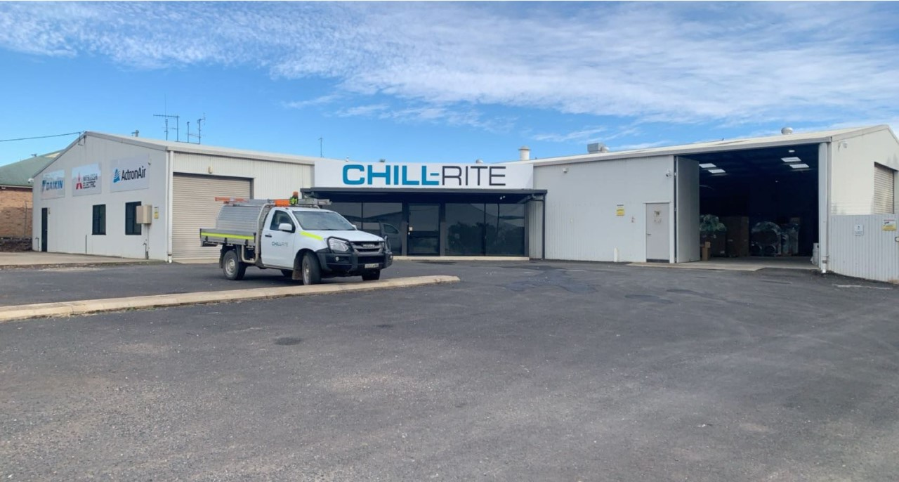 Exterior of Chill-Rite business with a truck parked in front. Gray building, blue sky, black asphalt— Chill-Rite Refrigeration and Air Conditioning in Coffs Harbour, NSW