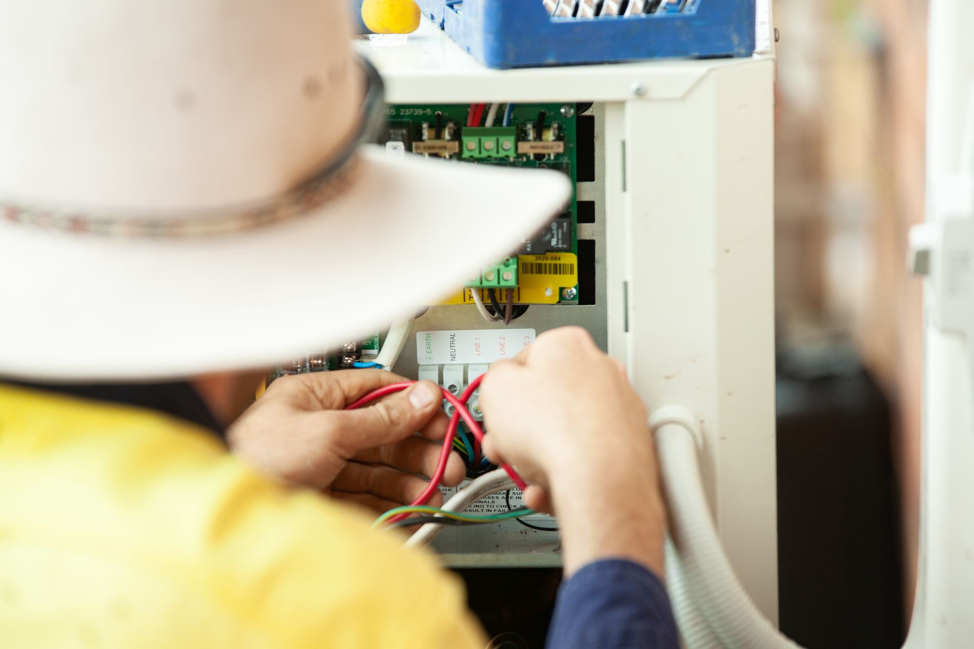 Electrician in a hat working on wiring inside an electrical box— Chill-Rite Refrigeration and Air Conditioning in Dubbo, NSW