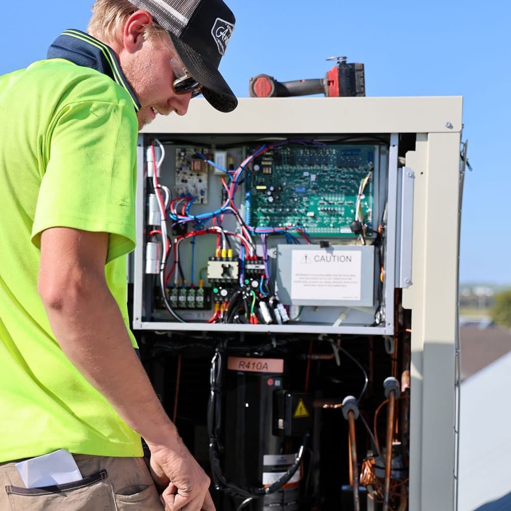 A Man is Working on a Machine With a Caution Sign on It — Chill-Rite Refrigeration and Air Conditioning in Dubbo, NSW
